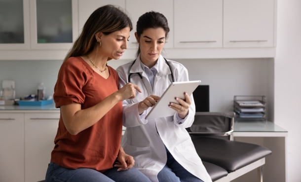 Woman wearing red top looking at test results with doctor wearing whiye coat