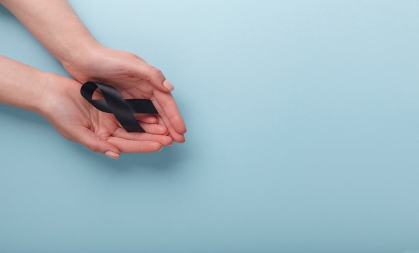 Person holding black gross ribbon in commemoration of melanoma patients