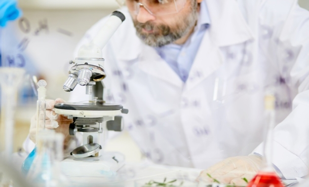 Scientist using a microscope to investigate respiratory viruses and cancer dormancy in a laboratory.