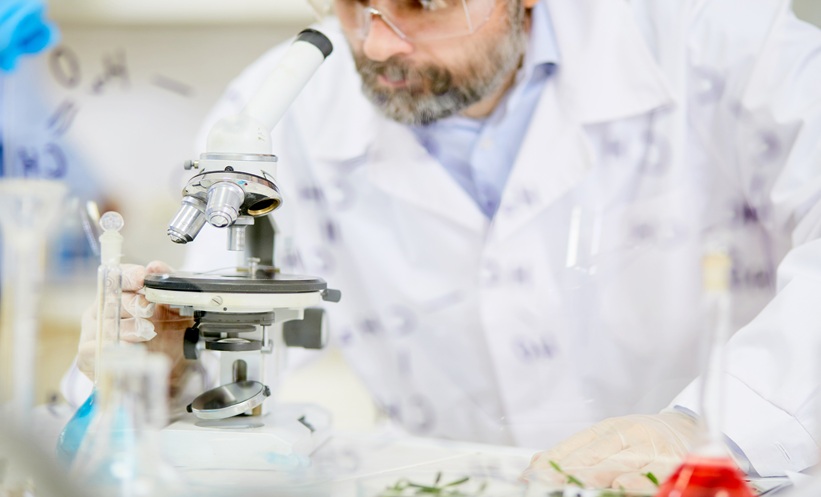 Scientist using a microscope to investigate respiratory viruses and cancer dormancy in a laboratory.