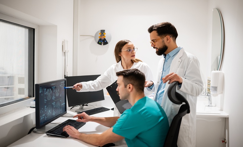 Medical imaging specialists reviewing diagnostic scans on a computer.