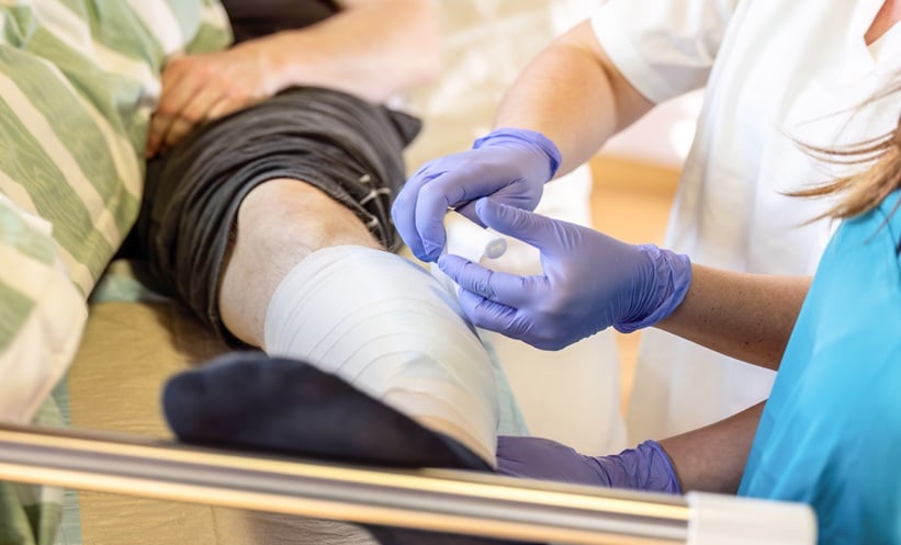 Clinician applying a dressing as part of moist wound healing care following skin graft surgery.
