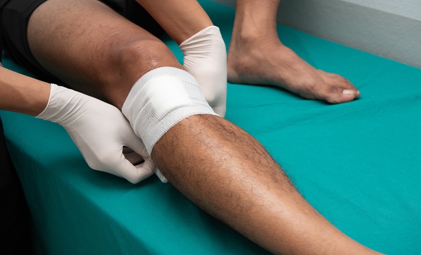 Healthcare professional dressing a patient’s leg wound following medical treatment.