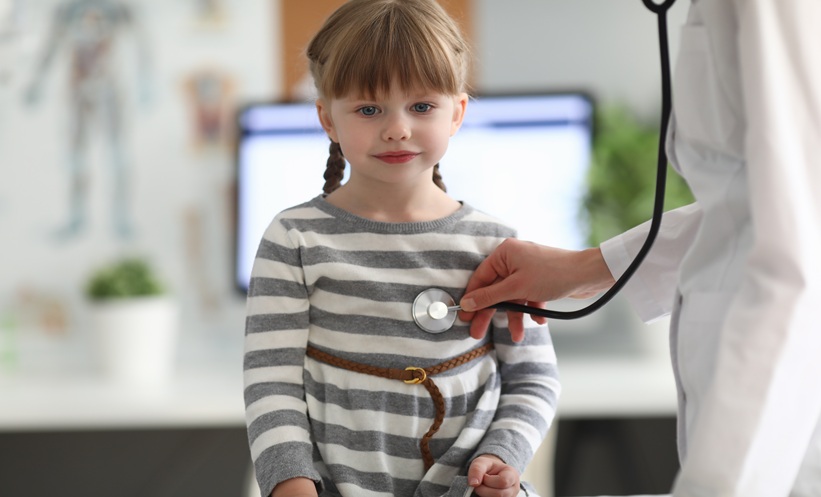 Clinician examining a young child, representing rising pediatric asthma ICU admissions.