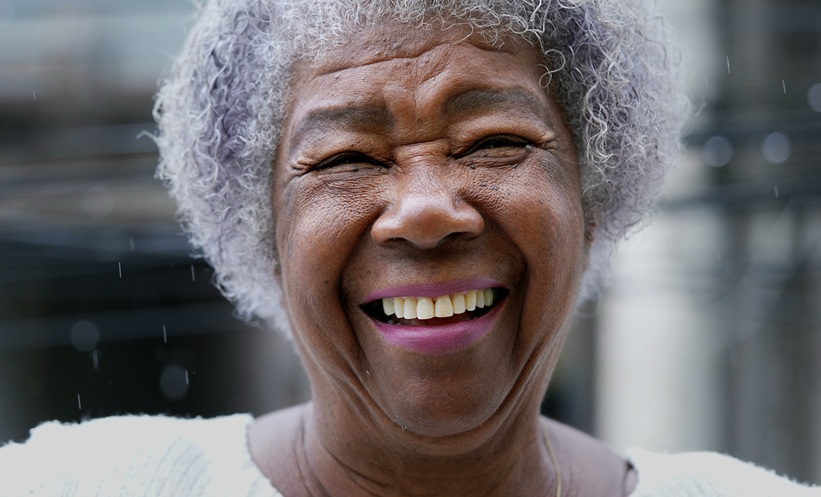 Older adult touching her face, illustrating research into the skin microbiome and aging.