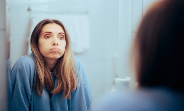 Woman looking at her reflection in a bathroom mirror.