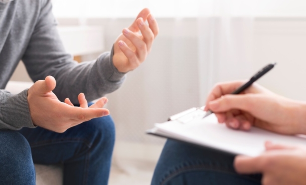Patient sits down with clinician who is writing down their health related concerns.