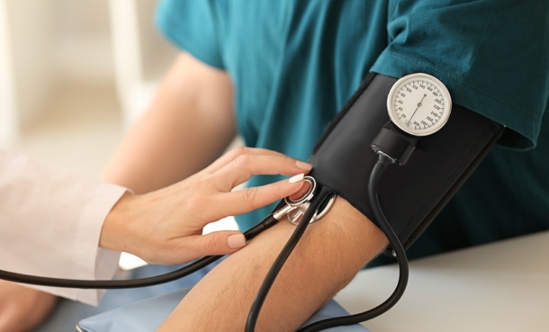 Man having his blood pressure taken with a black blood pressure cuff and a manual dial