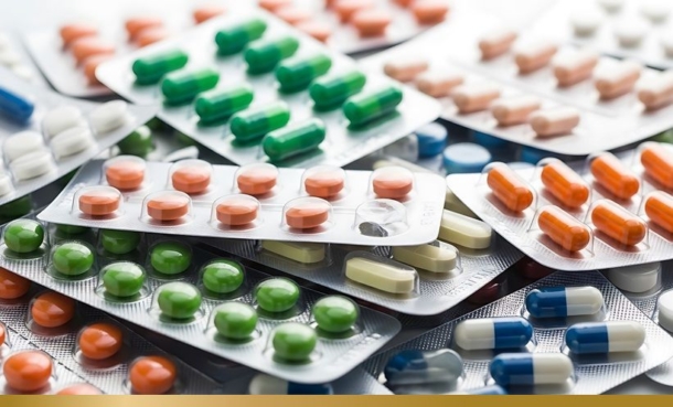 Foil blister packs of pills piled on top of each other, each with different sizes, colours and shapes of pills and oral treatments in them.