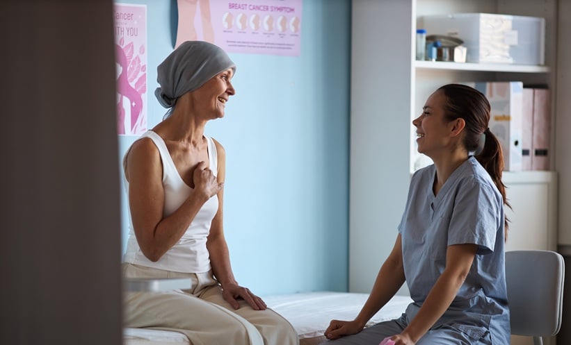 Woman with breast cancer talks to female nurse about her treatment