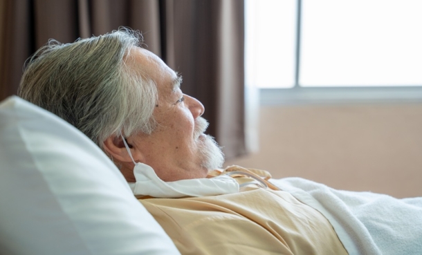 Older patient resting in a hospital bed during recovery after acute respiratory distress syndrome.