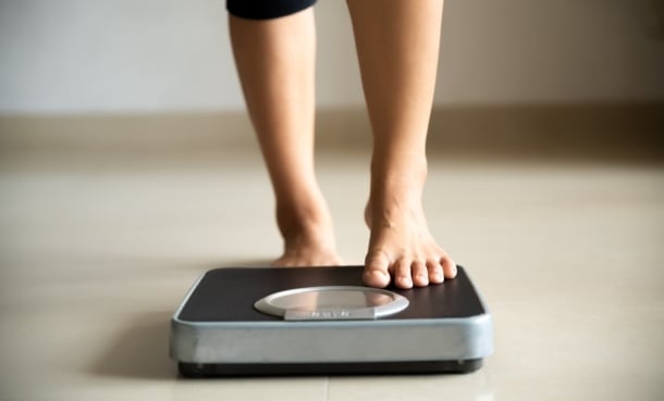 Person stepping onto the scales. petrelintide amylin in weight loss.