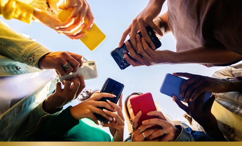 People standing in a circle looking at their phones together