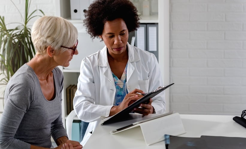 Woman with breast cancer being shown her scans by a doctor wearing a white lab coat